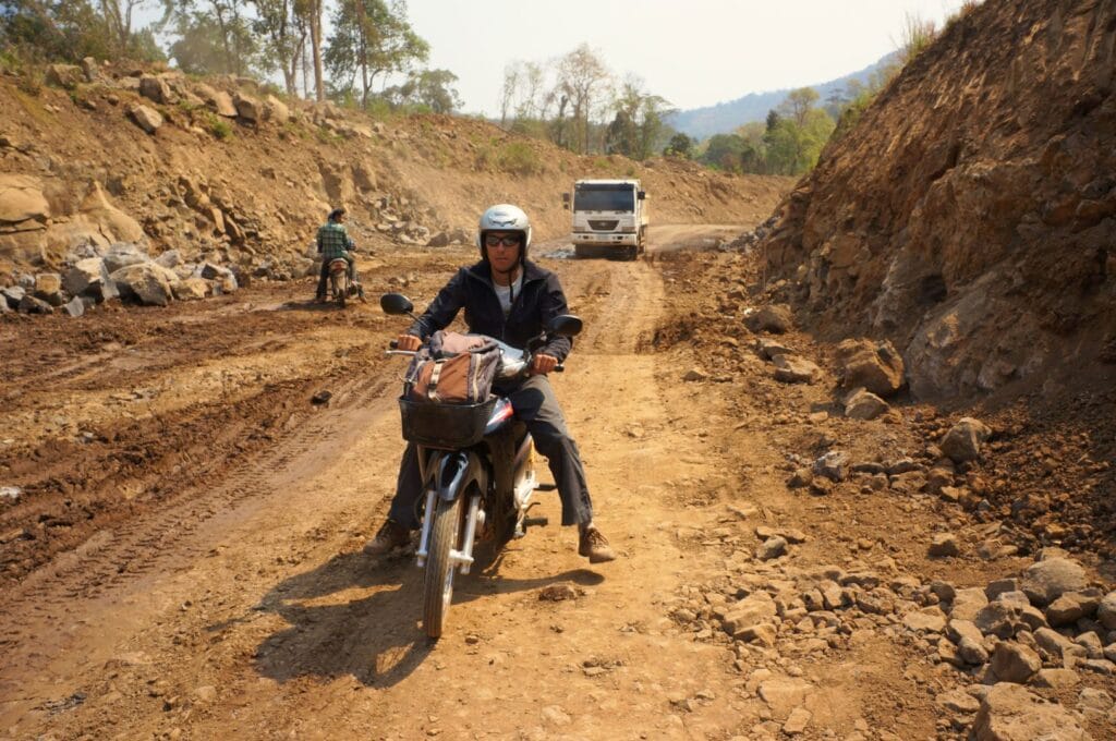 conduire à scooter sur une route défoncée du Laos